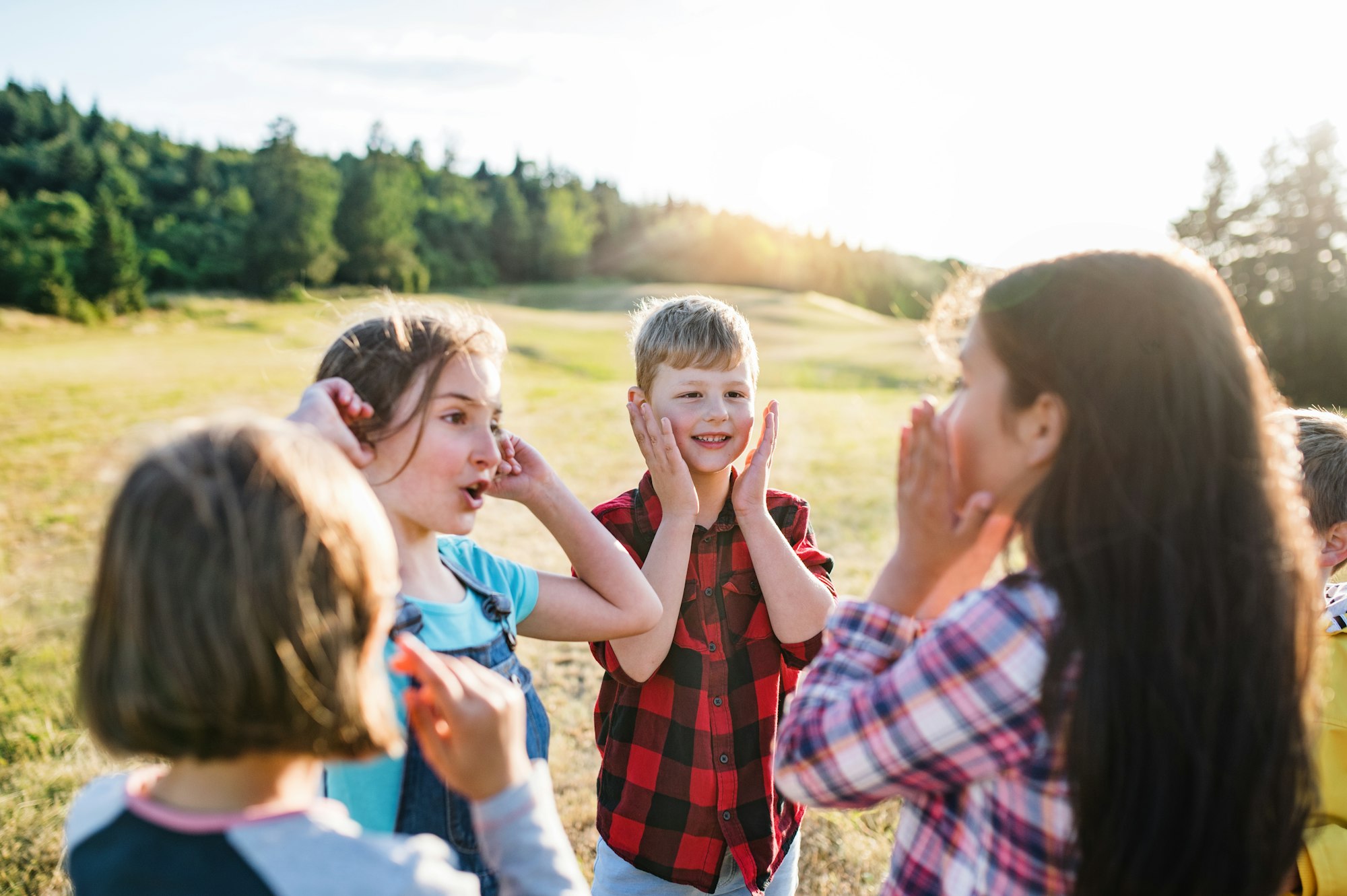 Group of school children standing on field trip in nature, playing