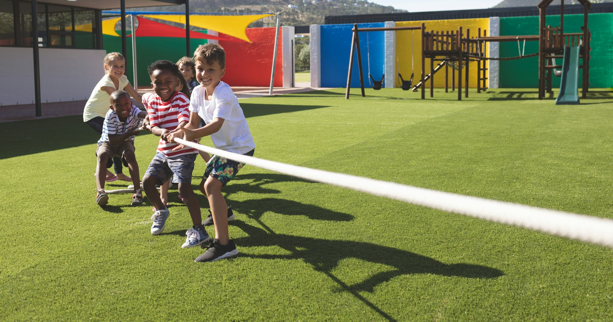 Group of school kids playing tug of war in playground